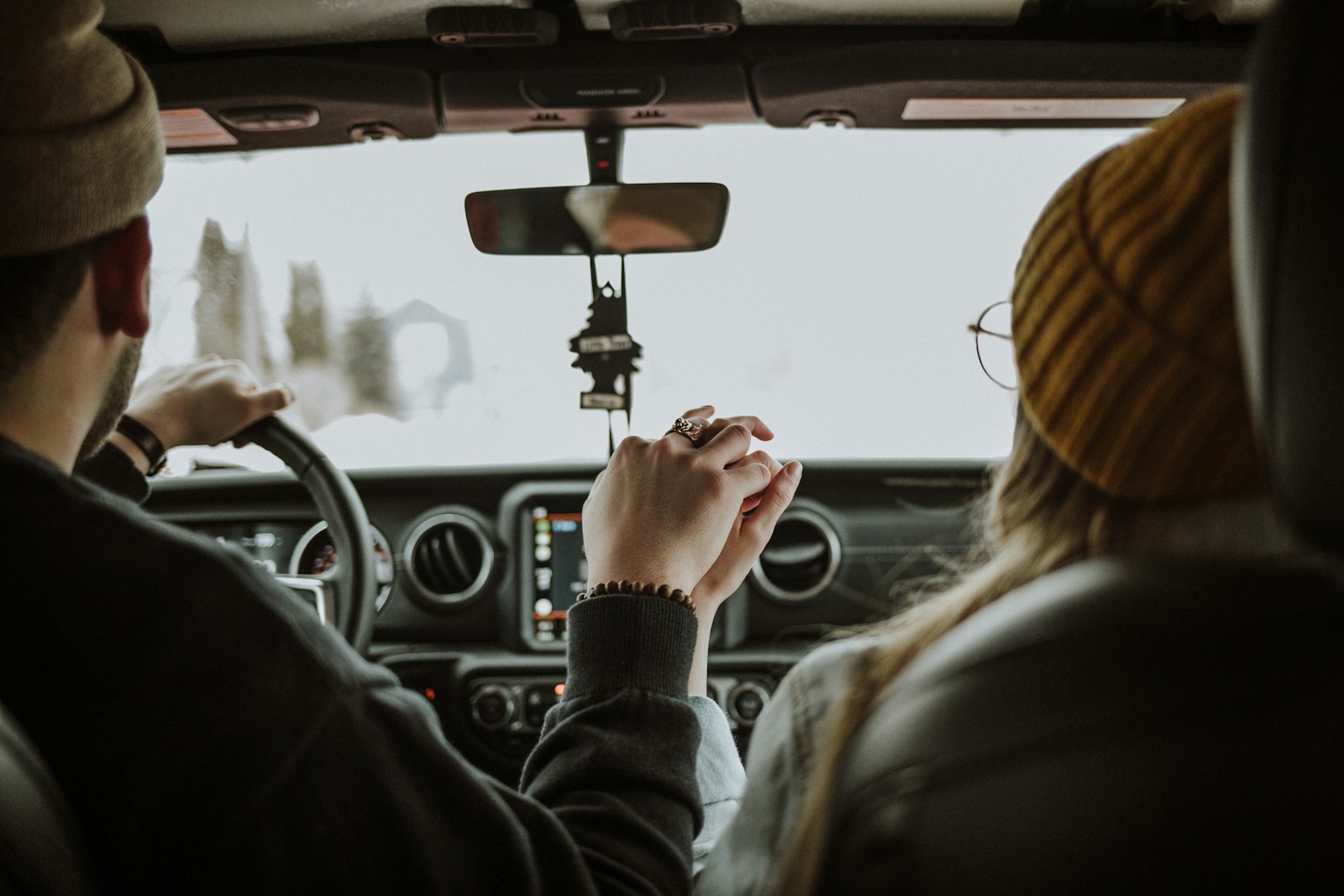 man driving car while holding woman's hand, auto